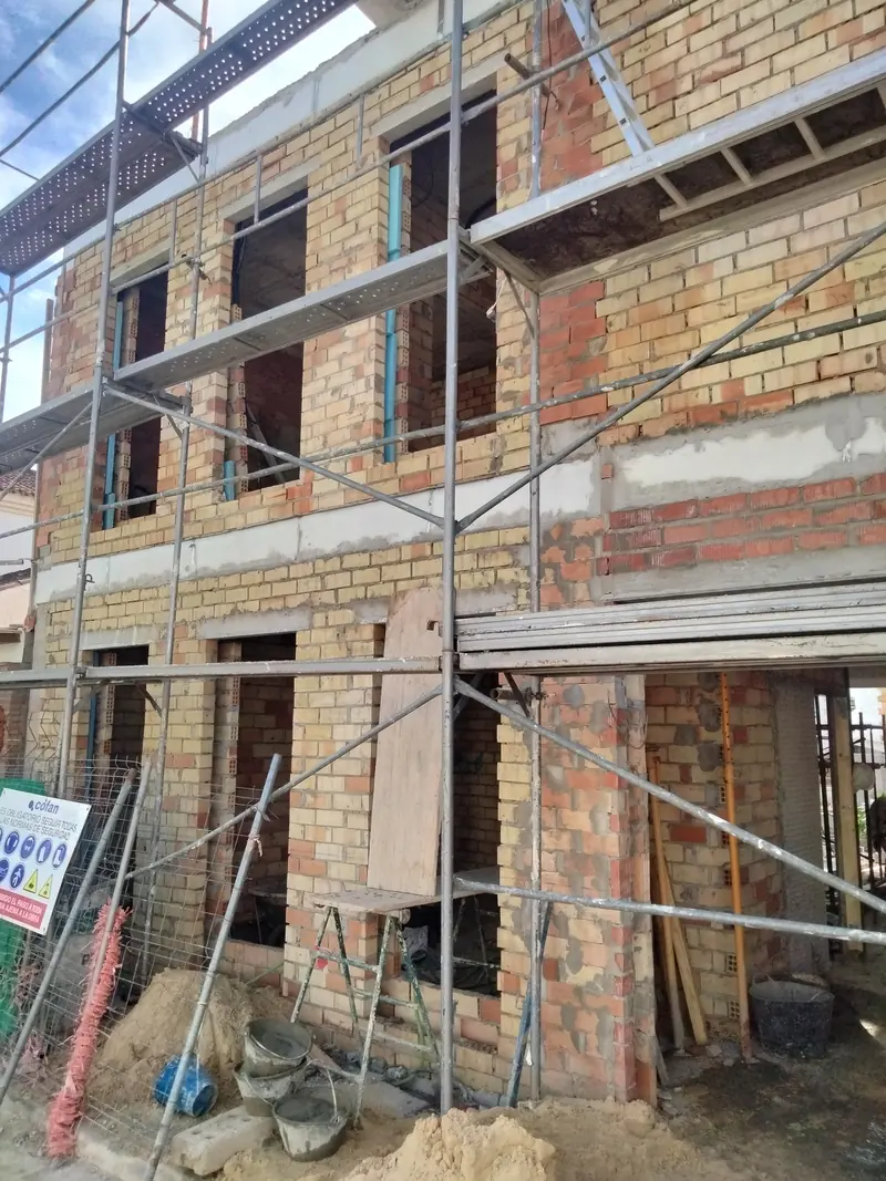 Vivienda de ladrillo con andamio durante la obra