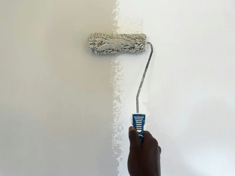 Rodillo pintando de blanco una pared lisa
